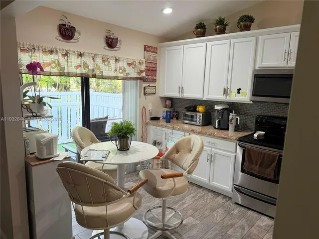 a kitchen with stainless steel appliances granite countertop a stove a sink dishwasher and white cabinets with wooden floor