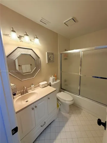 a bathroom with a toilet sink vanity granite and a mirror