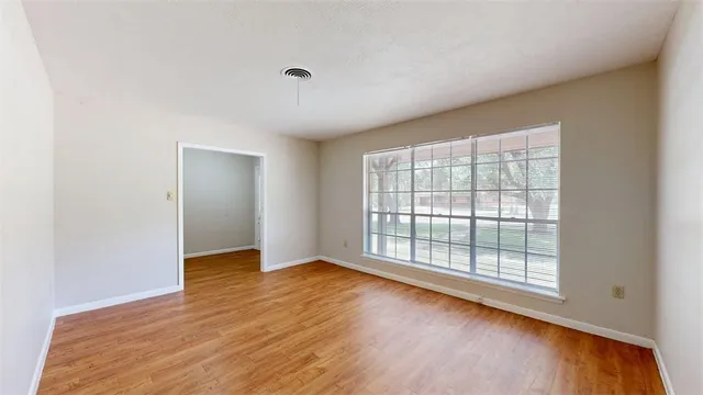 a view of an empty room with wooden floor and a window