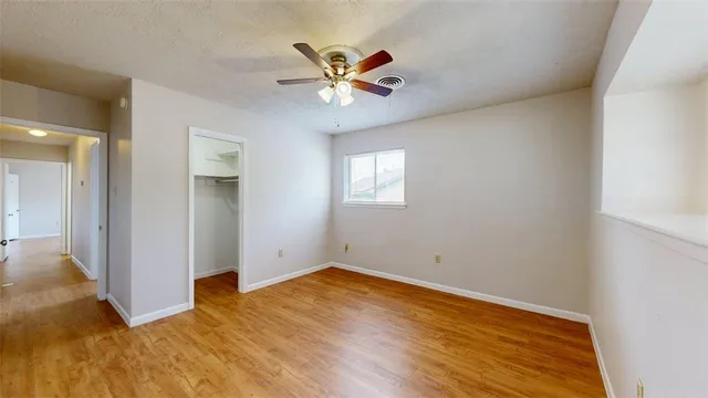an empty room with a window and a fan
