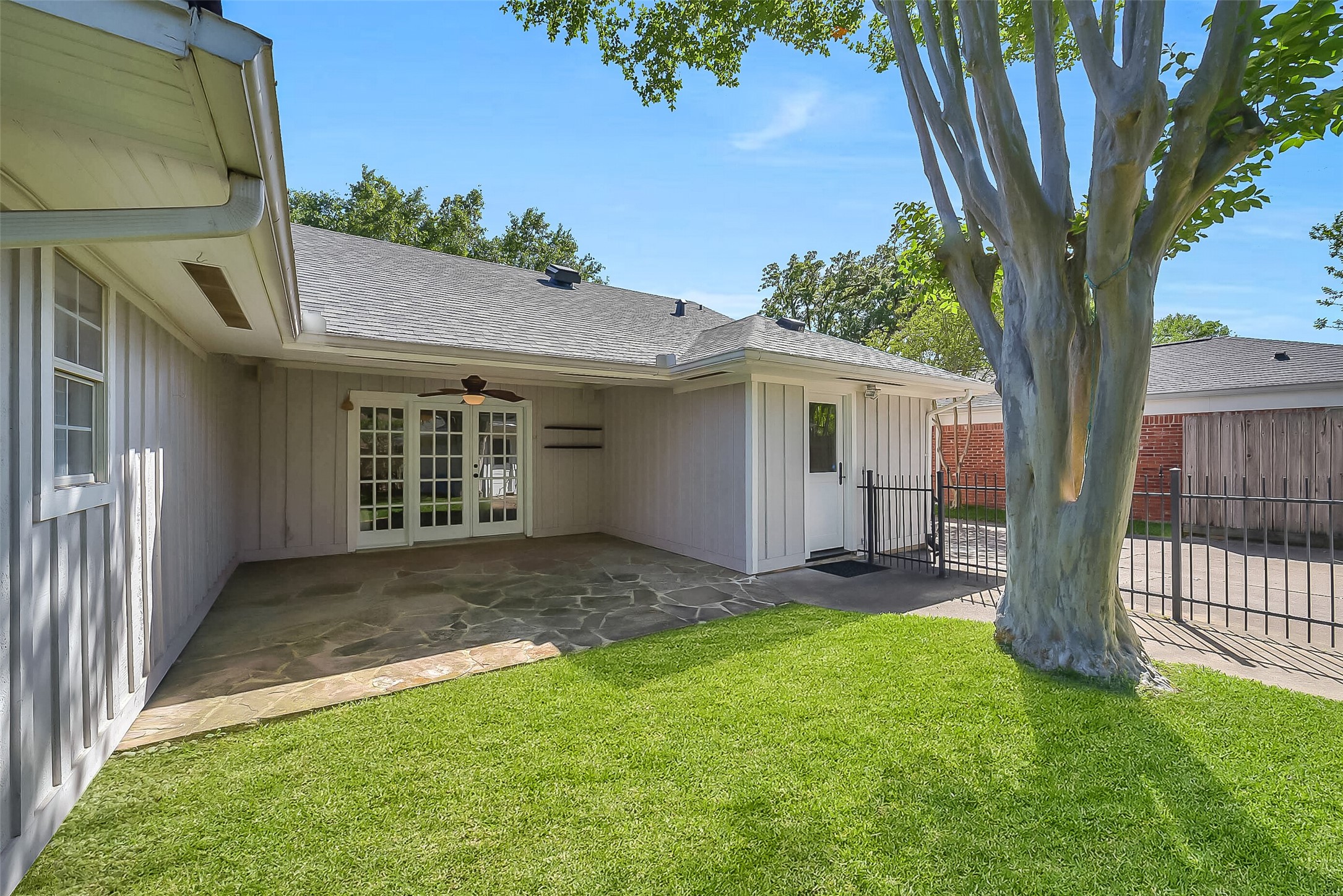 10026 Overbrook Lane Houston, TX 77042 - Photo 26 of 29 Thoughtfully designed outdoor layout includes a black wrought iron fence separating the yard from the driveway and a 2-car detached garage. Gutters already in place add to the home’s overall functionality and upkeep.
