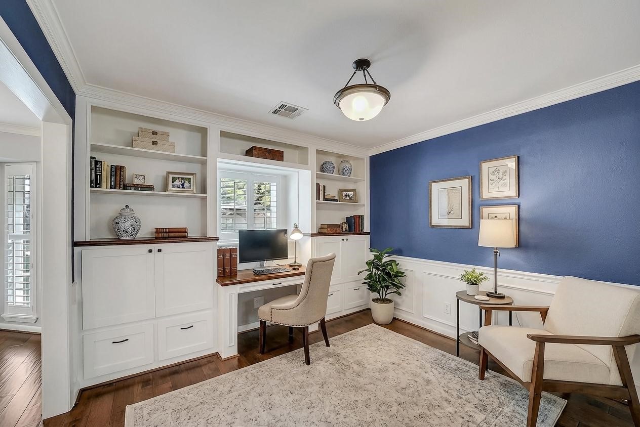 10026 Overbrook Lane Houston, TX 77042 - Photo 9 of 29 Well-appointed study featuring a wall of custom built-ins w/ shelving, desk, cabinets & drawers—ideal for a work-from-home setup. Navy painted accent walls w/ wainscoting and crown molding add character, while a front-facing window w/ plantation shutters brings in natural light.This photo is virtually staged.
