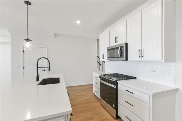 a kitchen with stainless steel appliances granite countertop a stove a sink and a white refrigerator with white countertops