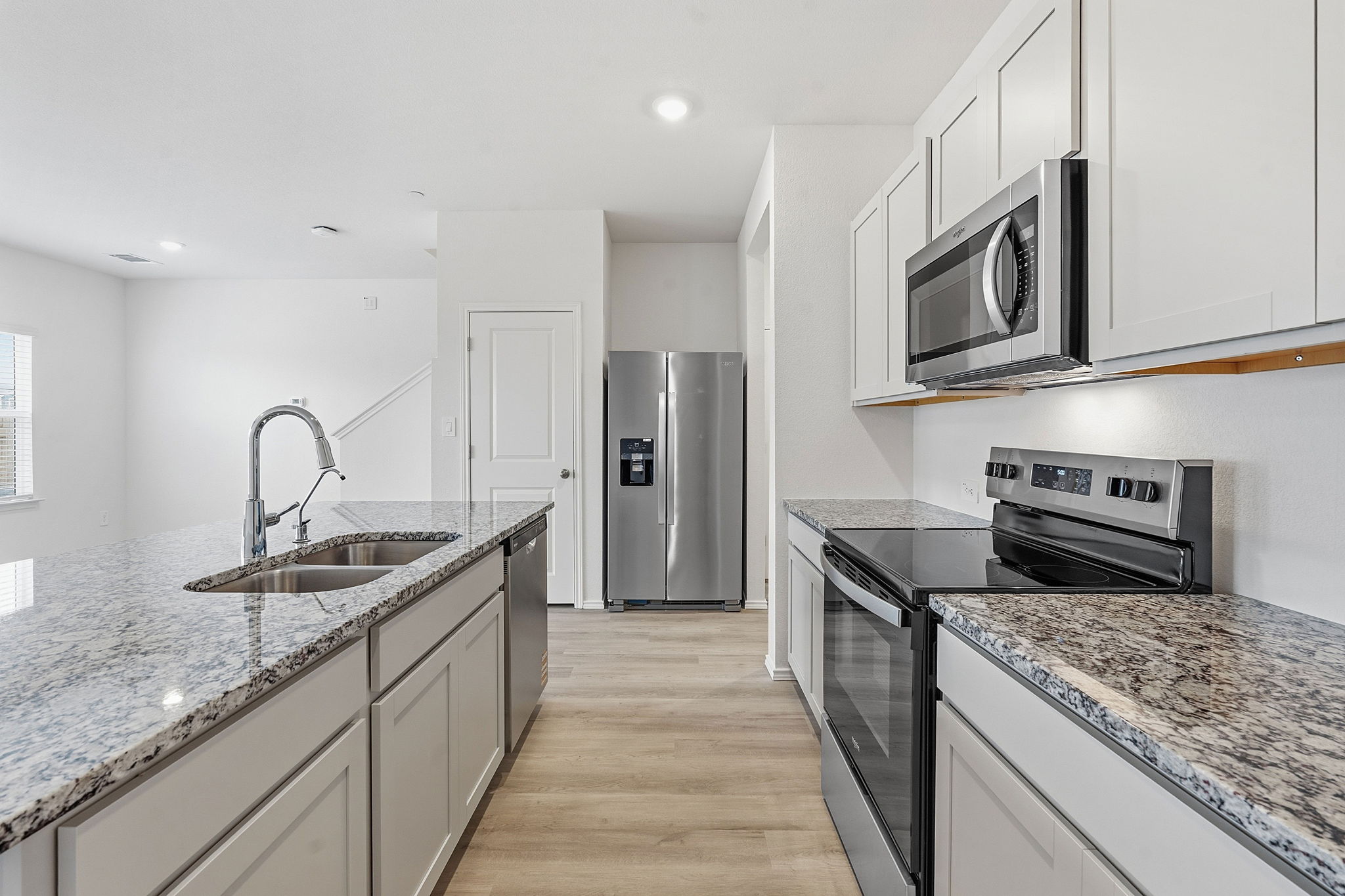 164 Cinnabar Lane, Unit 3 Kyle, TX 78640 - Photo 7 of 20 Kitchen featuring granite countertops, stainless steel appliances, light wood-finish flooring, white cabinetry, and a double basin sink with a high-arc faucet