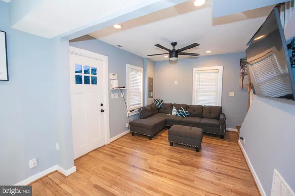 a living room with couches and a flat screen tv with wooden floor