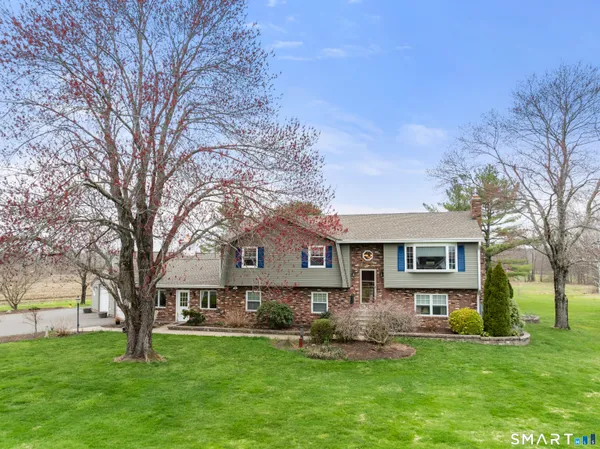 a view of a house with a big yard plants and large trees