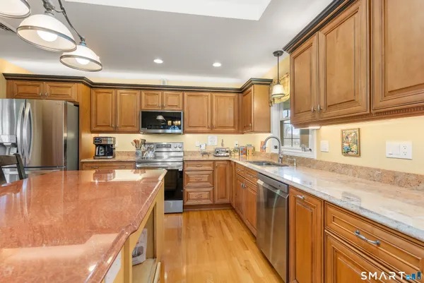 a kitchen with kitchen island granite countertop wooden floor and stainless steel appliances