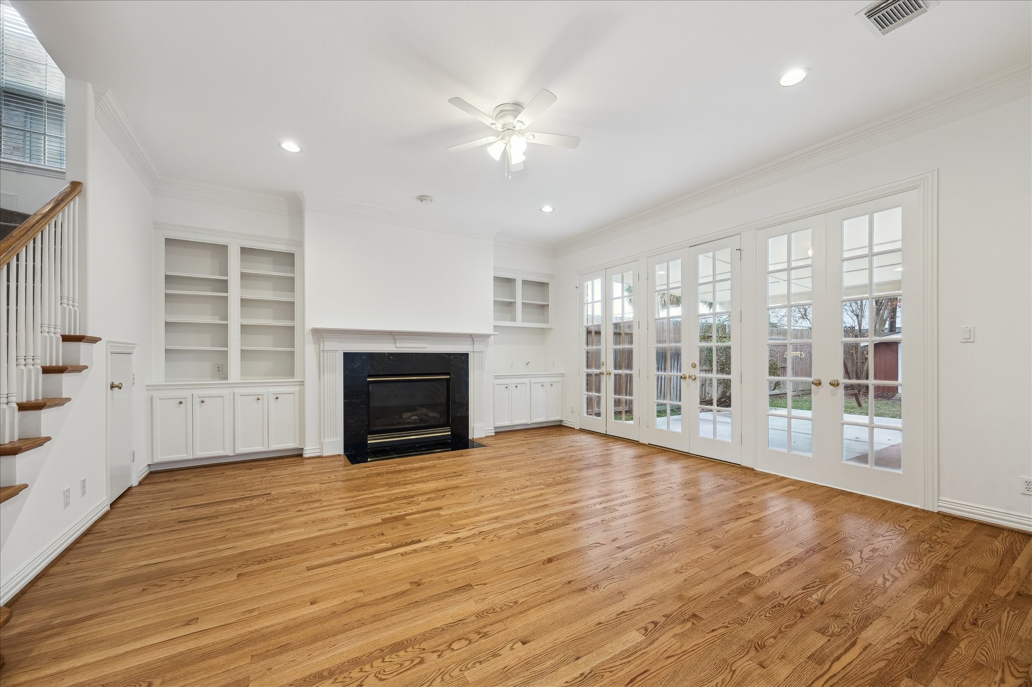 5107 Locust Street Bellaire, TX 77401 - Photo 12 of 45 Spacious family room with hardwood floors, a fireplace flanked by custom built-ins, recessed lighting, & French doors that open to the covered patio and backyard, creating a seamless indoor-outdoor connection for everyday living and entertaining.