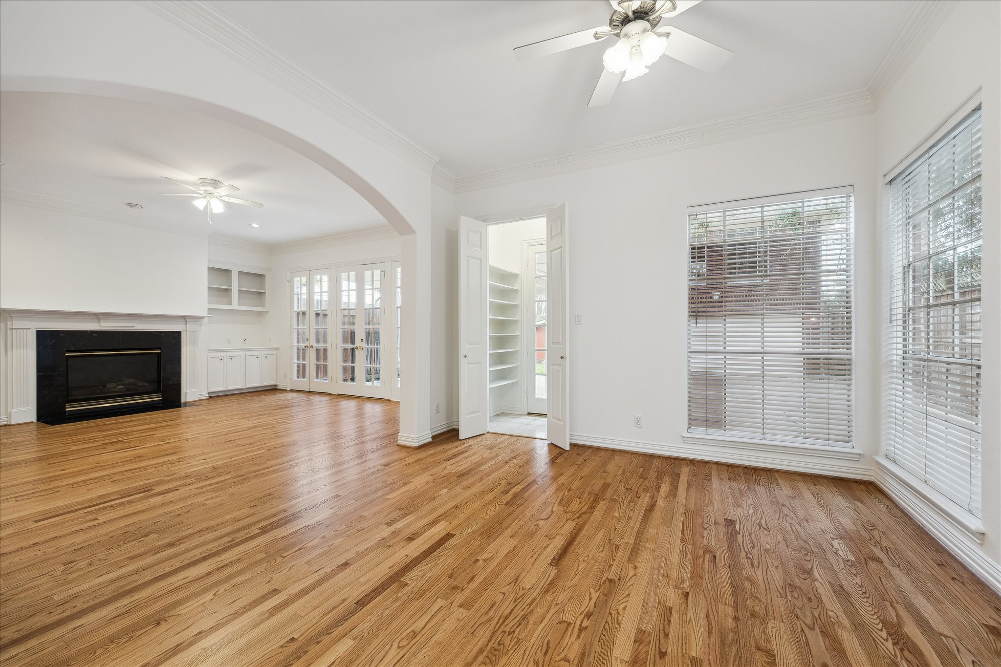 5107 Locust Street Bellaire, TX 77401 - Photo 14 of 45 Open view of the breakfast room and family room highlighting hardwood floors, crown molding, & arched openings that create a natural connection between the two spaces—well suited for casual dining, gathering, and everyday living.
