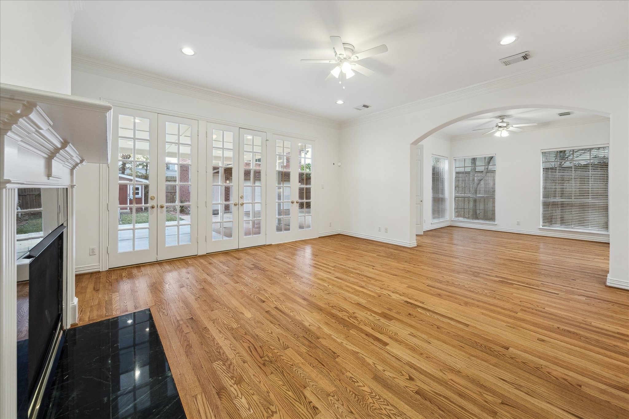 5107 Locust Street Bellaire, TX 77401 - Photo 17 of 45 Spacious family room with rich hardwood floors, detailed crown molding, & expansive sightlines that highlight the home’s open, light-filled layout. Elegant architectural openings and refined finishes create a polished setting.