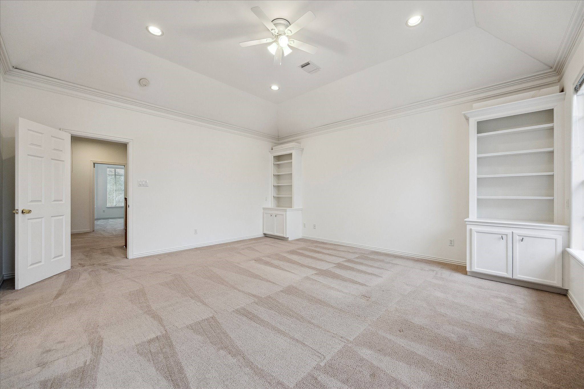 5107 Locust Street Bellaire, TX 77401 - Photo 26 of 45 Additional view of the spacious primary bedroom showcasing vaulted ceilings, crown molding, recessed lighting, & custom built-in cabinetry, creating a light-filled retreat with thoughtful architectural detail.