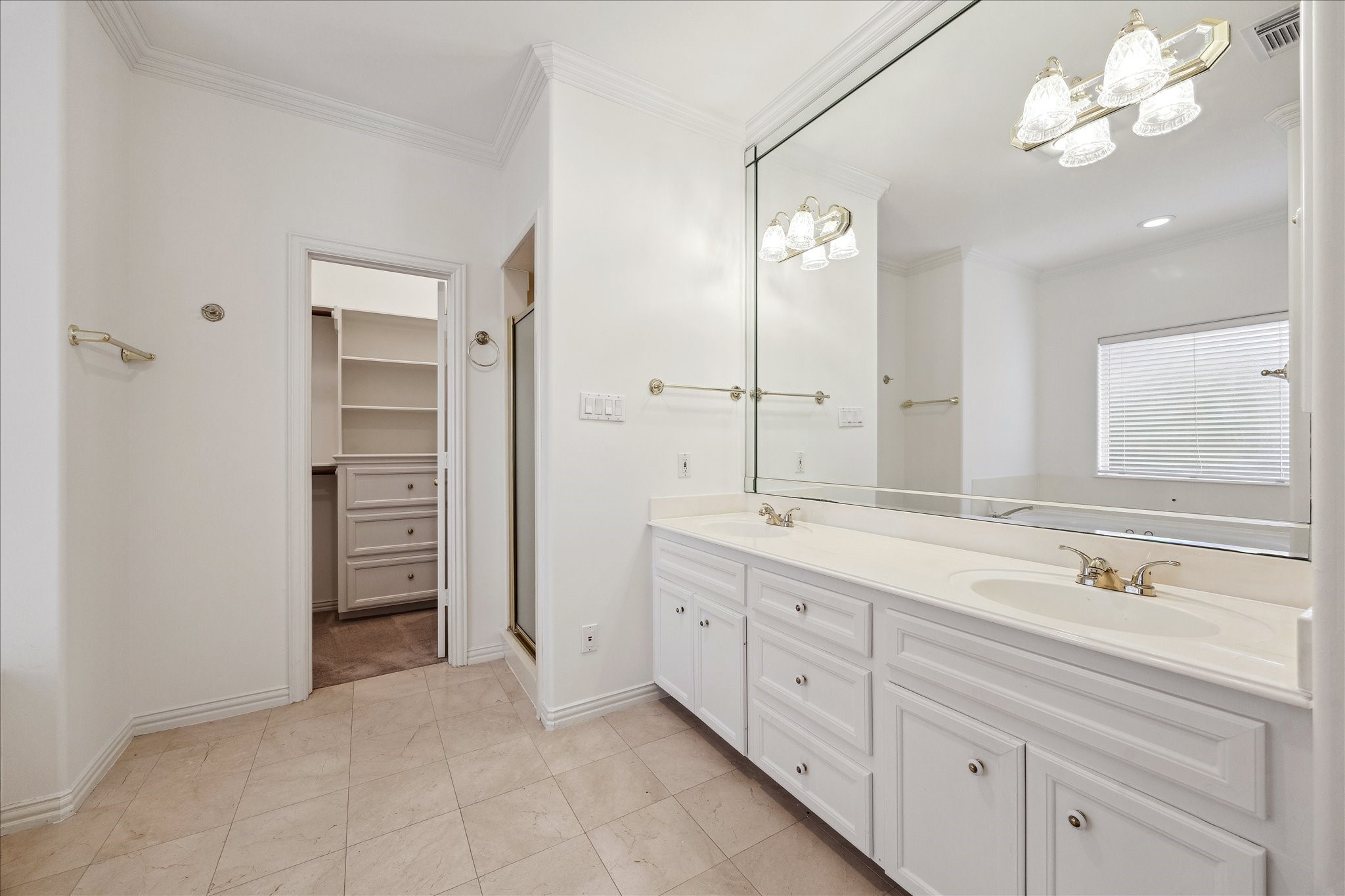 5107 Locust Street Bellaire, TX 77401 - Photo 27 of 45 Primary ensuite featuring an extended dual-sink vanity with excellent cabinetry, a large mirror, crown molding, & updated lighting—designed for both everyday ease and refined functionality.