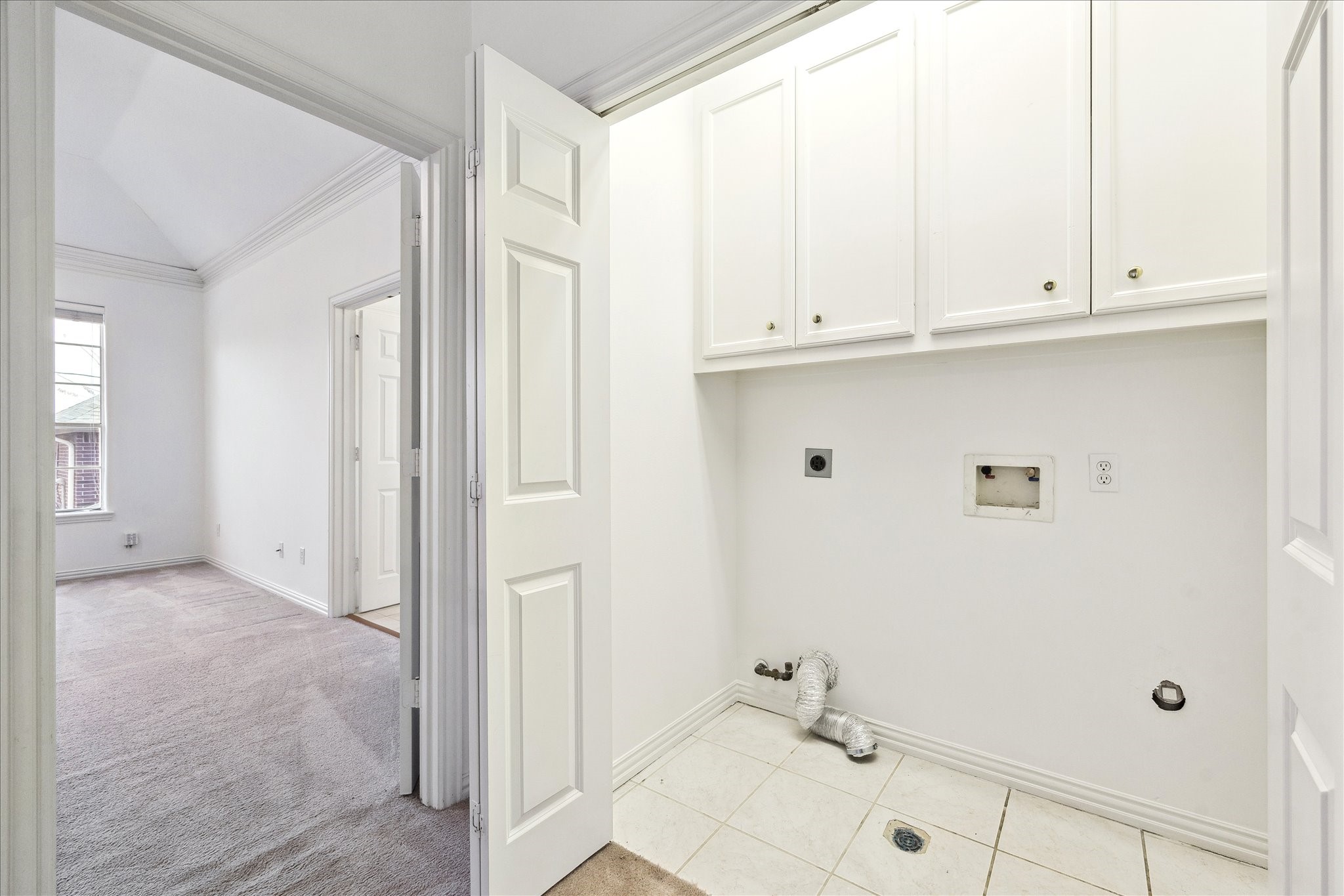 5107 Locust Street Bellaire, TX 77401 - Photo 35 of 45 Convenient upstairs utility room located near the bedrooms, offering dedicated washer & dryer connections, built-in upper cabinetry, and tiled flooring—designed for everyday functionality right where you need it.