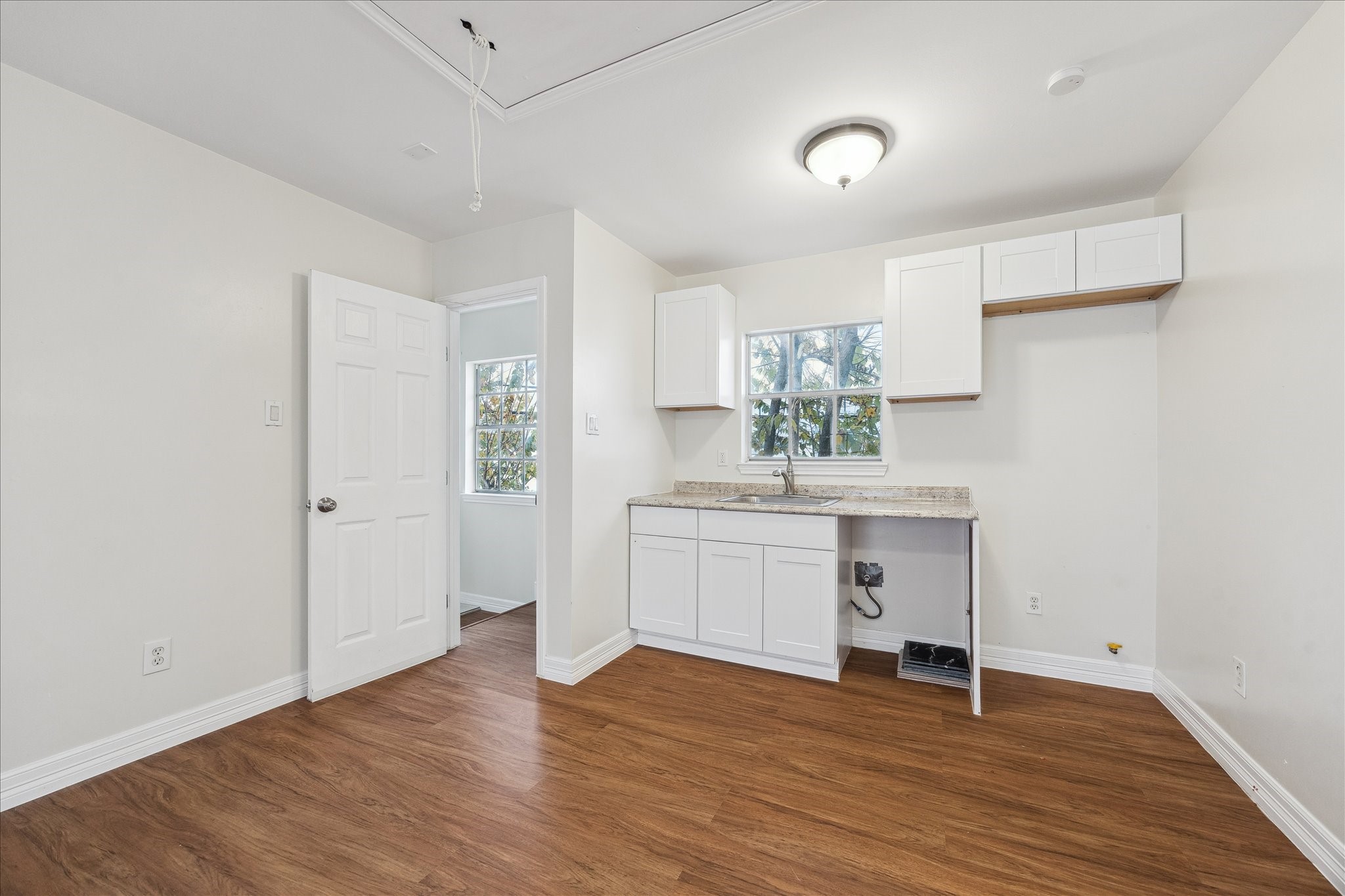 5107 Locust Street Bellaire, TX 77401 - Photo 37 of 45 Detached garage apartment offering a versatile layout with a kitchenette, washer & dryer hookups, and wood flooring. Bright interior with cabinetry, counter space, and a sink—well suited for guest accommodations or additional living space with separation from the main residence.