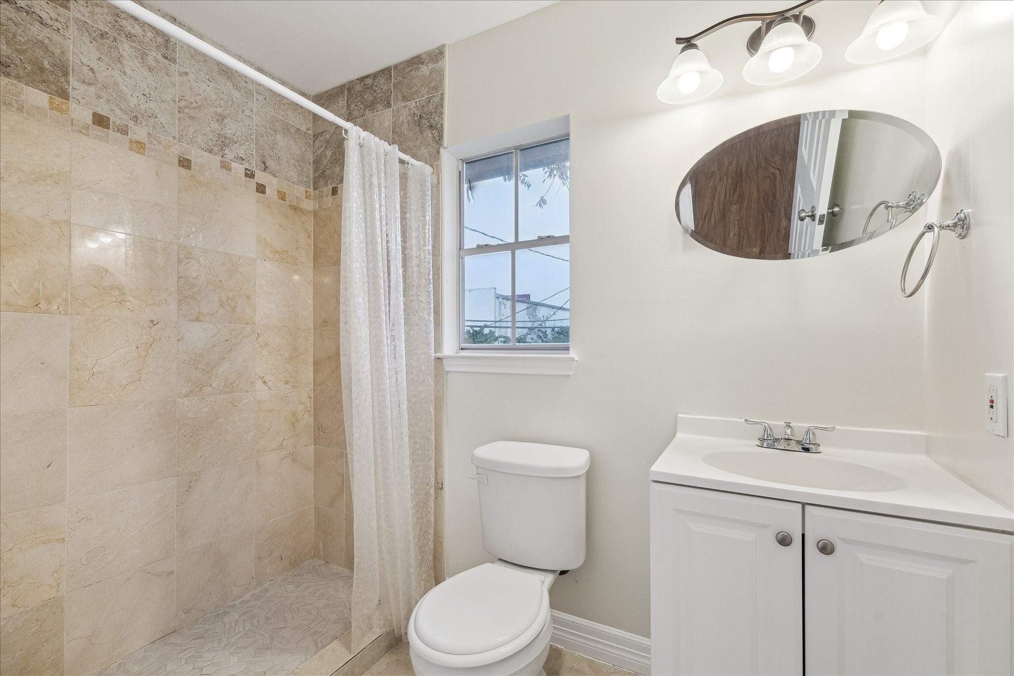 5107 Locust Street Bellaire, TX 77401 - Photo 38 of 45 Full bath featuring a walk-in, tiled shower, updated vanity with storage, and a window that brings in natural light. Crisp finishes and a functional layout make this space ideal for guest use or independent living within the garage apartment.