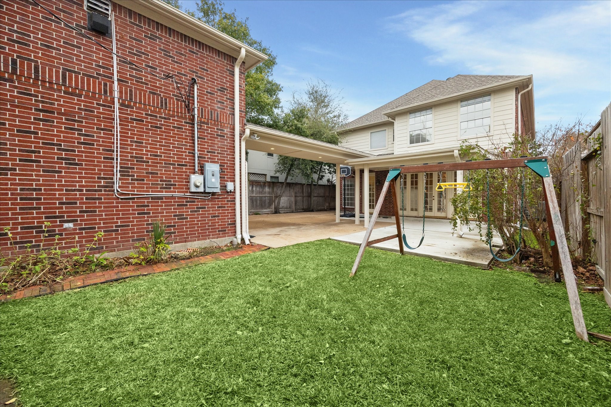 5107 Locust Street Bellaire, TX 77401 - Photo 41 of 45 Spacious backyard showcases a lush grassy area ready for play, gatherings, or quiet relaxation. The covered patio enhances the outdoor experience, providing year-round enjoyment and easy flow between the home and garage apartment.
