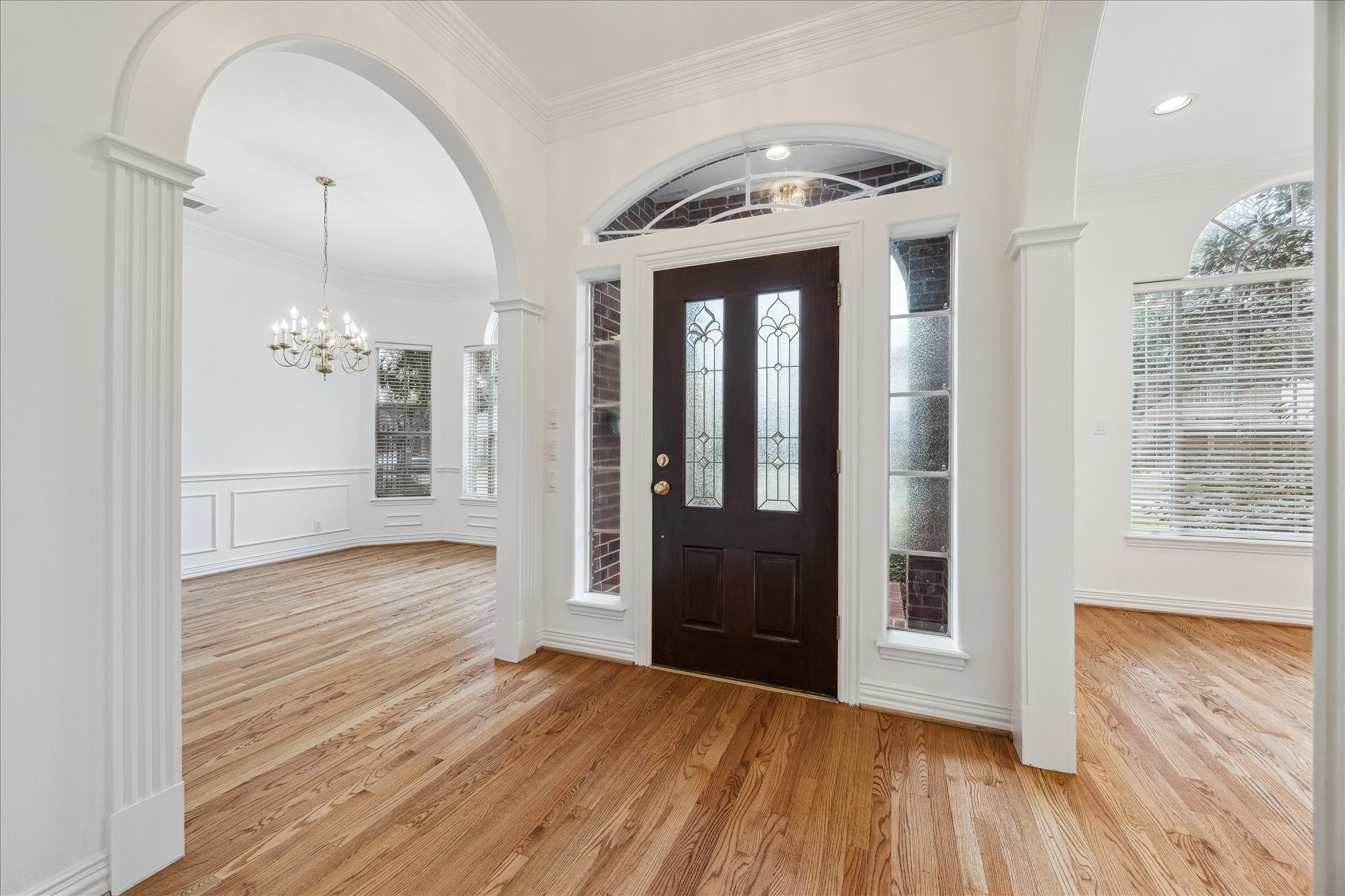 5107 Locust Street Bellaire, TX 77401 - Photo 5 of 45 Light-filled entry featuring a single front door with sidelights & arched transom, hardwood floors, crown molding, & elegant arched openings leading to formal living & dining spaces.