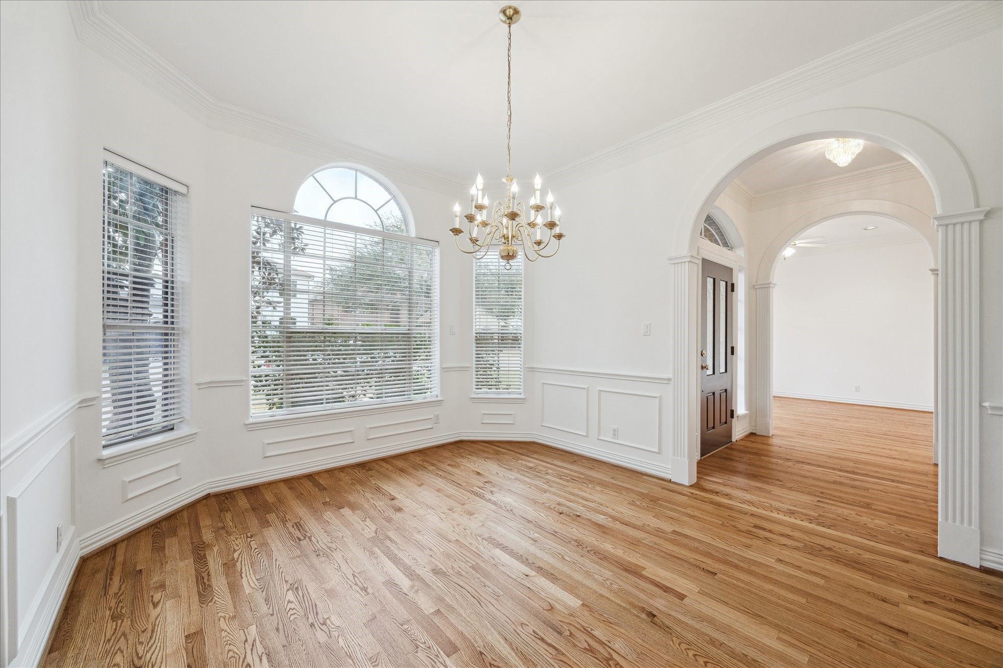 5107 Locust Street Bellaire, TX 77401 - Photo 9 of 45 Another perspective of the formal dining room showcasing the graceful arched window, detailed millwork, & refined chandelier, with an open connection to the nearby living room that enhances flow for entertaining.