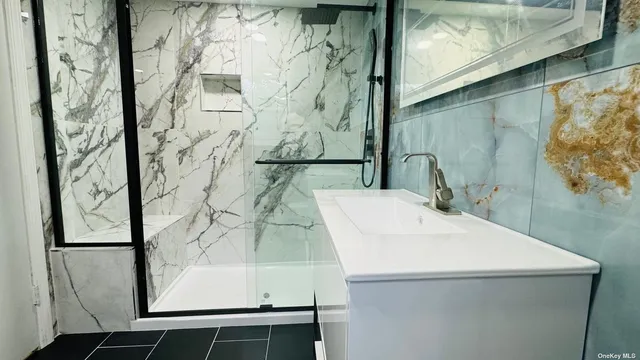 a bathroom with a sink and mirror with bathtub