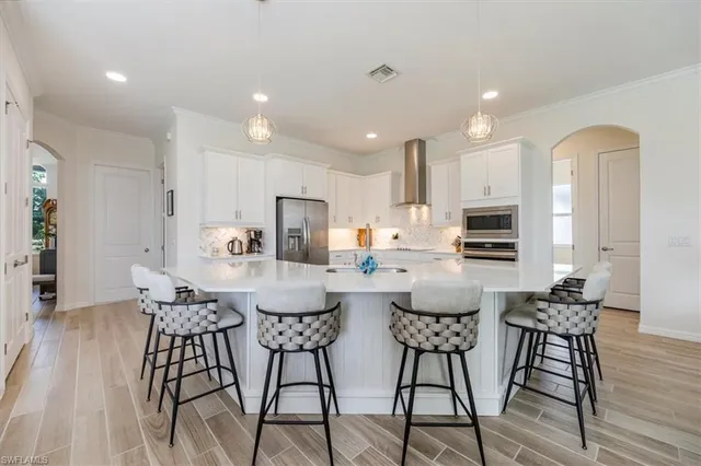 a kitchen with stainless steel appliances kitchen island granite countertop a dining table chairs and a refrigerator