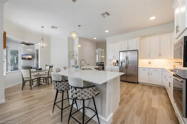 a kitchen with stainless steel appliances a dining table chairs stove refrigerator and cabinets