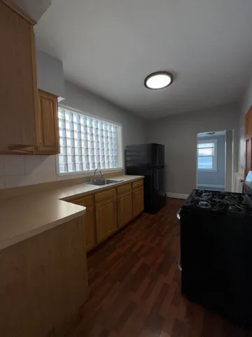 a kitchen with stainless steel appliances granite countertop a sink a stove a refrigerator cabinets and a dining table