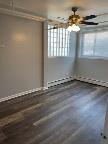 an empty room with wooden floor fan and windows