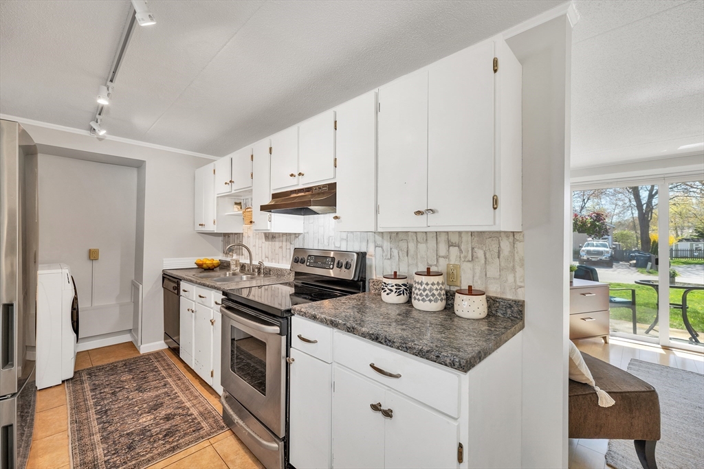 64 Esker Road, Unit 2 Hampton, NH 03842 - Photo 7 of 35 a kitchen with kitchen island granite countertop a sink stove and cabinets