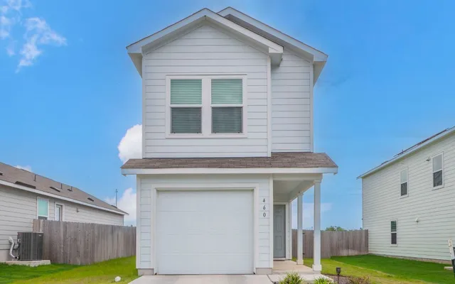 a view of a house with backyard and wooden fence