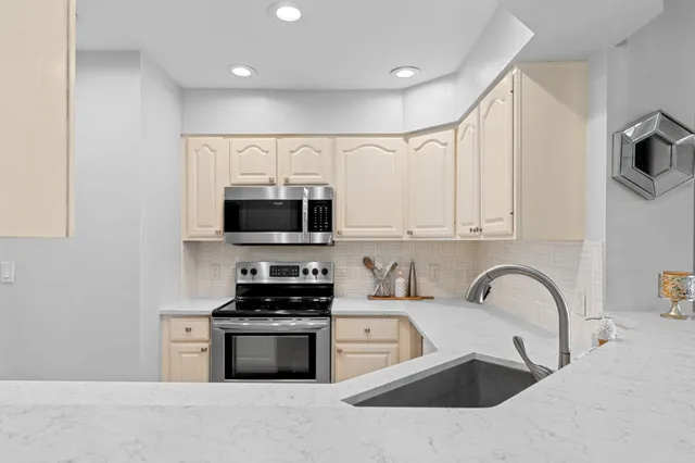 a kitchen with stainless steel appliances granite countertop a sink a stove and a refrigerator