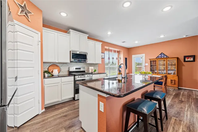 a kitchen with stainless steel appliances granite countertop a sink a stove and a refrigerator