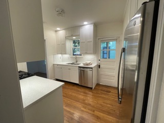 1305 East 28th Street, Unit A Austin, TX 78722 - Photo 9 of 15 Kitchen with stainless steel appliances, white cabinets, light countertops, dark wood-type flooring, and decorative backsplash