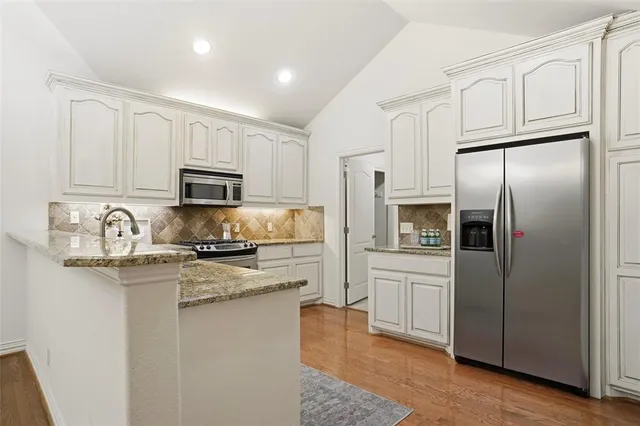 a kitchen with stainless steel appliances granite countertop a refrigerator a stove microwave and sink