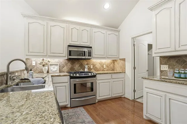 a kitchen with stainless steel appliances granite countertop a stove a sink dishwasher and a refrigerator
