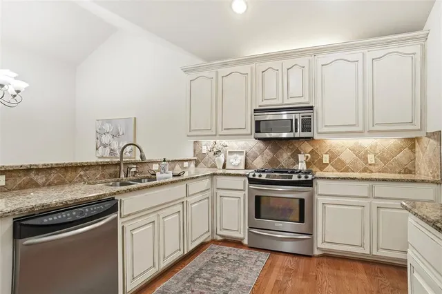 a kitchen with granite countertop a sink stainless steel appliances and cabinets