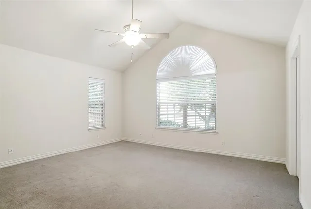 an empty room with a chandelier fan and windows