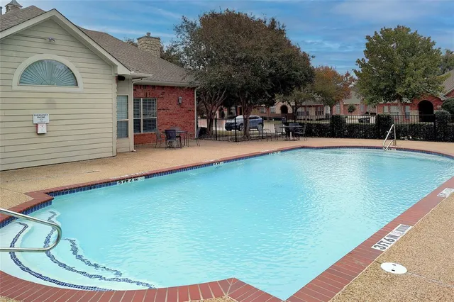a view of swimming pool with outdoor seating and trees in the background