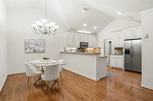 a kitchen with stainless steel appliances granite countertop a sink dishwasher a refrigerator with wooden floor and cabinets