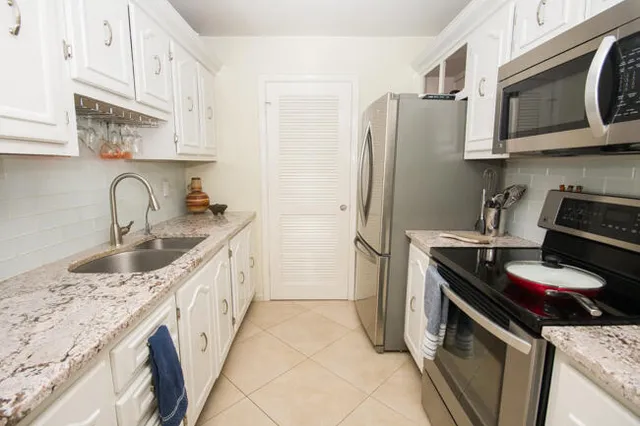 a kitchen with stainless steel appliances granite countertop a sink stove refrigerator and cabinets