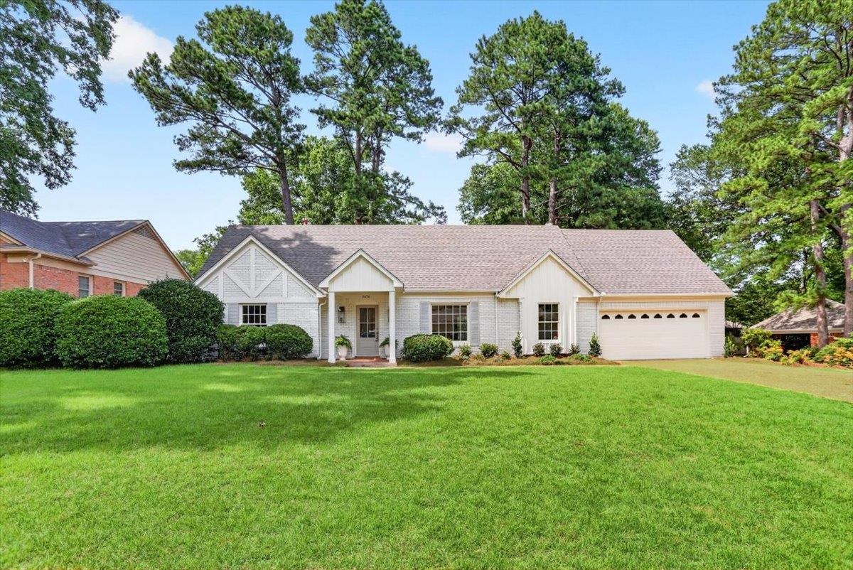 7674 Apple Valley Road Germantown, TN 38138 - Photo 1 of 15 White brick residence featuring a gray shingle roof, attached garage, gabled architectural elements, and mature landscaping
