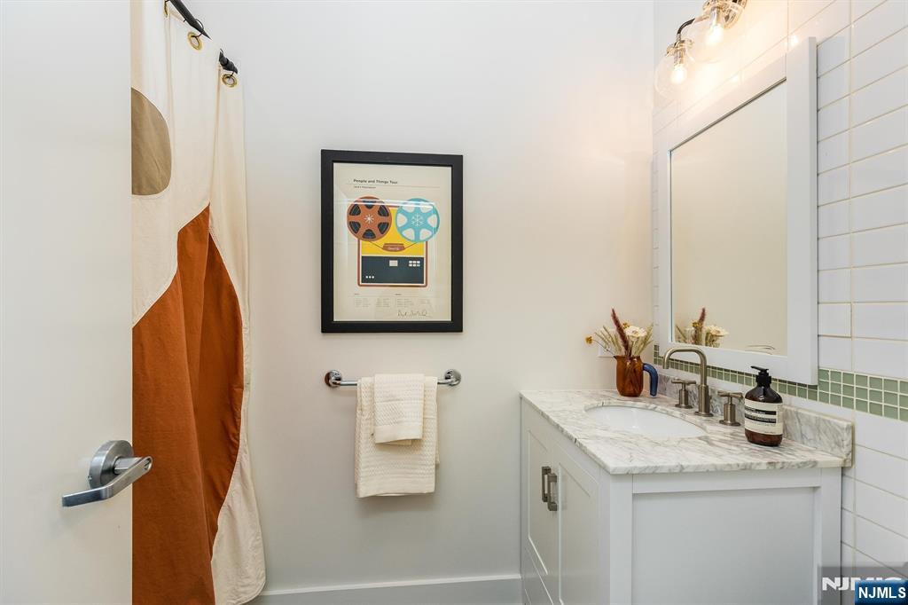 25 Clark Street, Unit 205 Glen Ridge, NJ 07028 - Photo 20 of 28 a bathroom with a granite countertop sink and a mirror