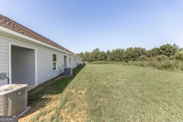 a view of a backyard with plants and large trees
