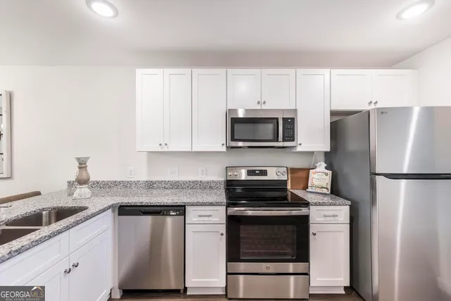 a kitchen with refrigerator a microwave a sink and cabinets