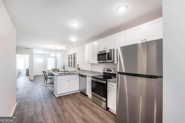 a kitchen with a refrigerator a stove top oven a sink dishwasher and a dining table with wooden floor