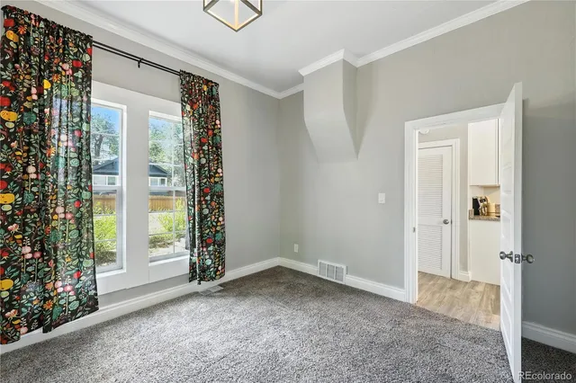 a view of an empty room with window and chandelier fan