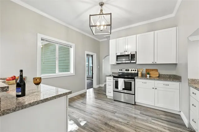 a large kitchen with granite countertop a stove top oven a sink dishwasher and a refrigerator with wooden floor