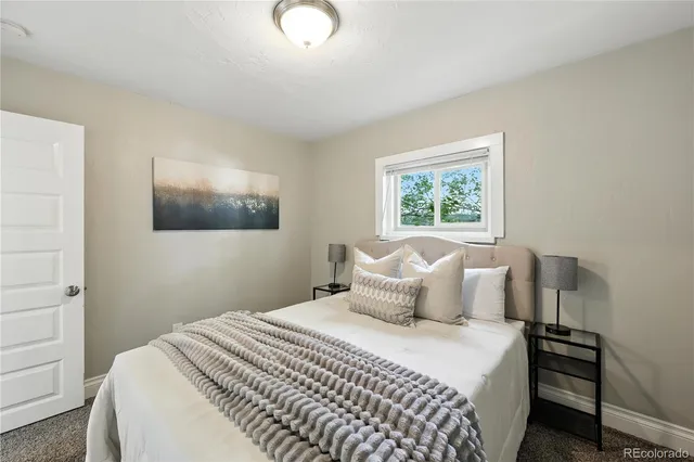 a bedroom with a bed and a large mirror next to a window