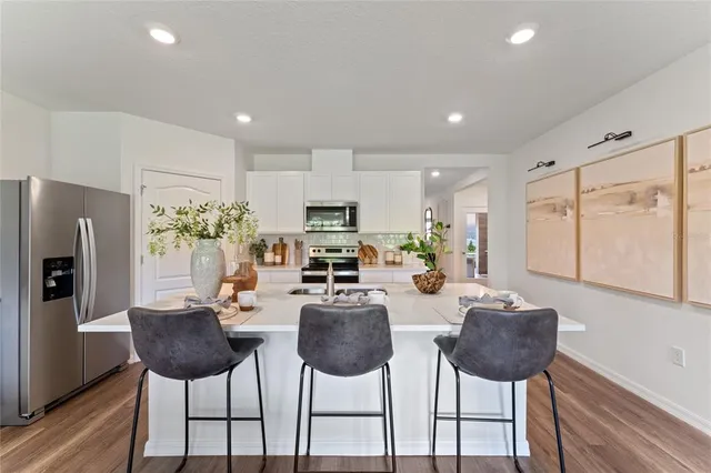 a kitchen with stainless steel appliances kitchen island granite countertop a refrigerator and a dining table