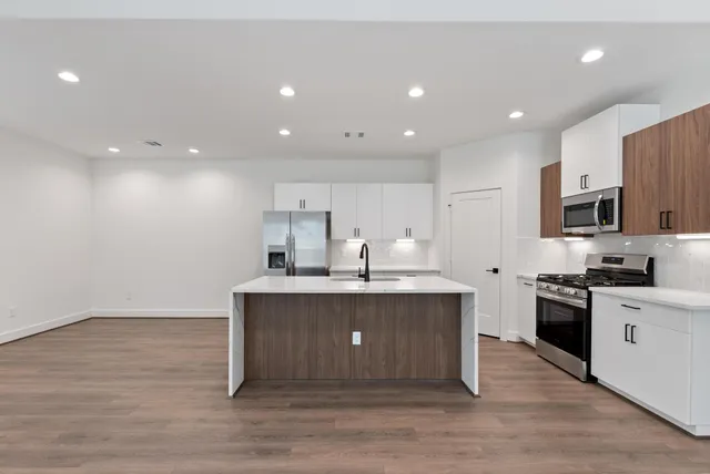 a kitchen with stainless steel appliances a sink stove and wooden floor