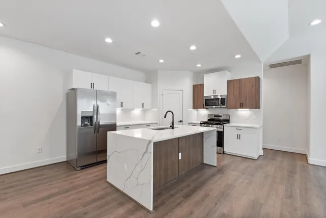 a kitchen with stainless steel appliances kitchen island hardwood floor sink and stove